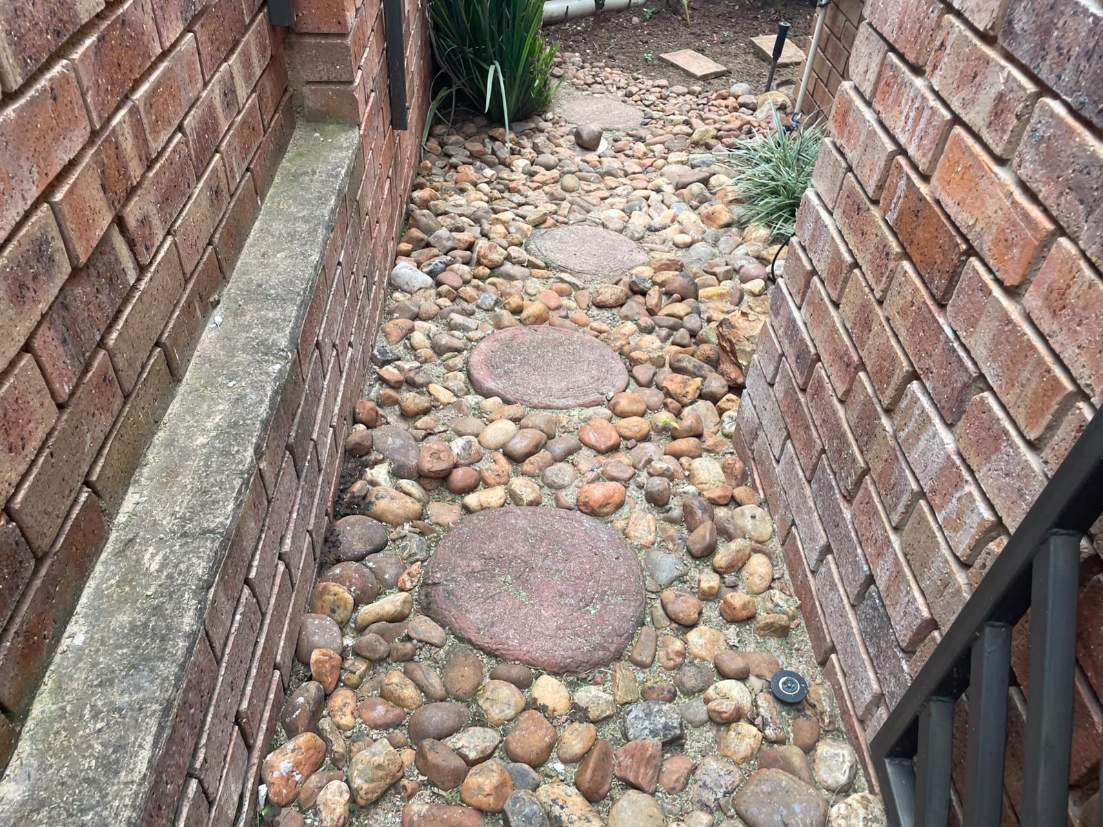 Overgrown pebble walkway to crisp tiled passage — before